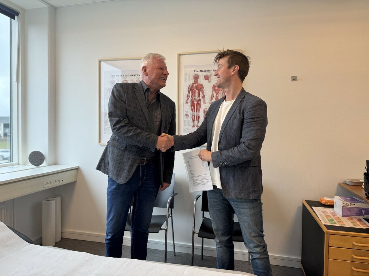 To mænd giver håndtryk på Radteam kontor, symbol på samarbejde og radiologiske løsninger i Danmark.
